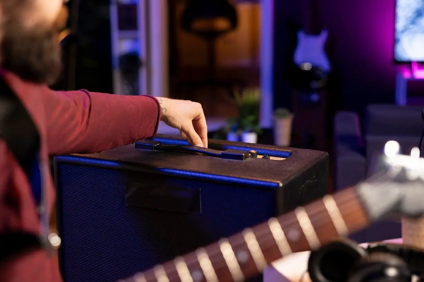 Звукорежиссёр регулирует уровни громкости на усилителе для записи гитарных мелодий.